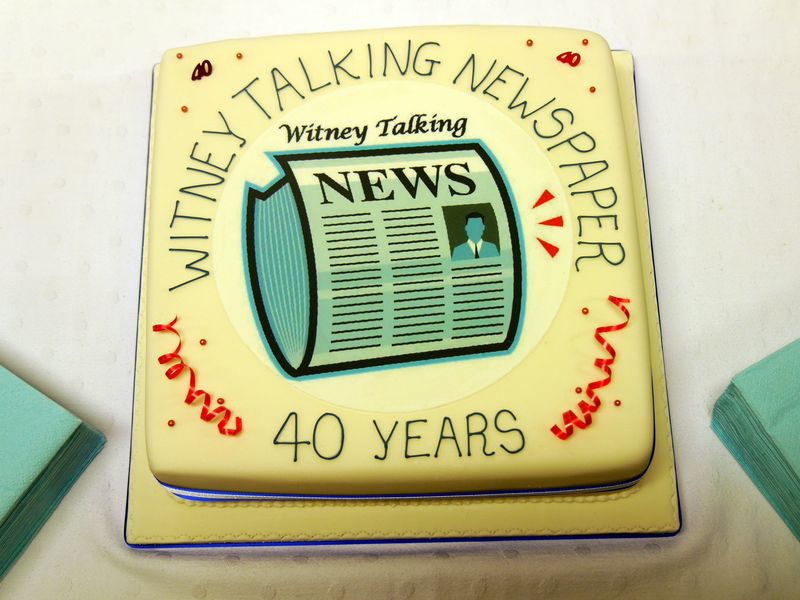 Plain white fondant covered cake depicting the WTN logo at the centre surrounded by the text "Witney Talking News 40 Years".